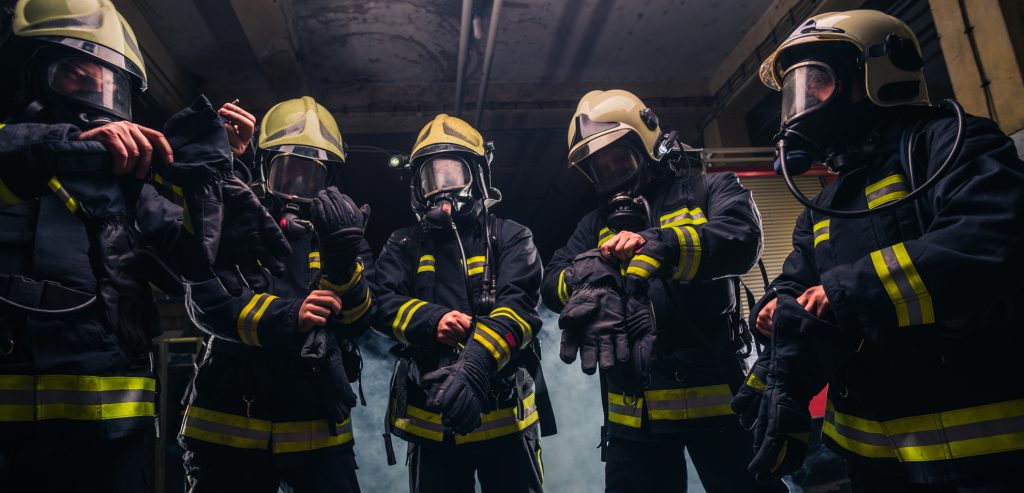 Team of firefighters in the fire department wearing gas masks and uniform